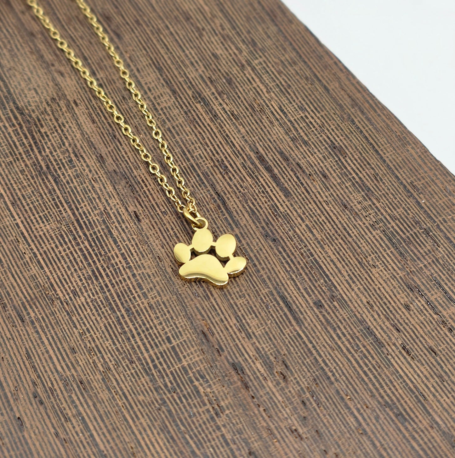 Gold paw print necklace on a wooden surface