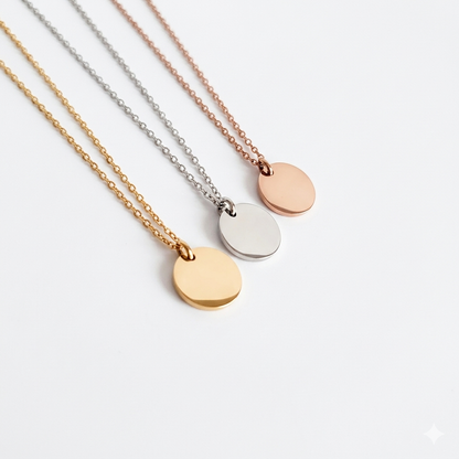 Three gold necklaces with round pendants on a light gray background