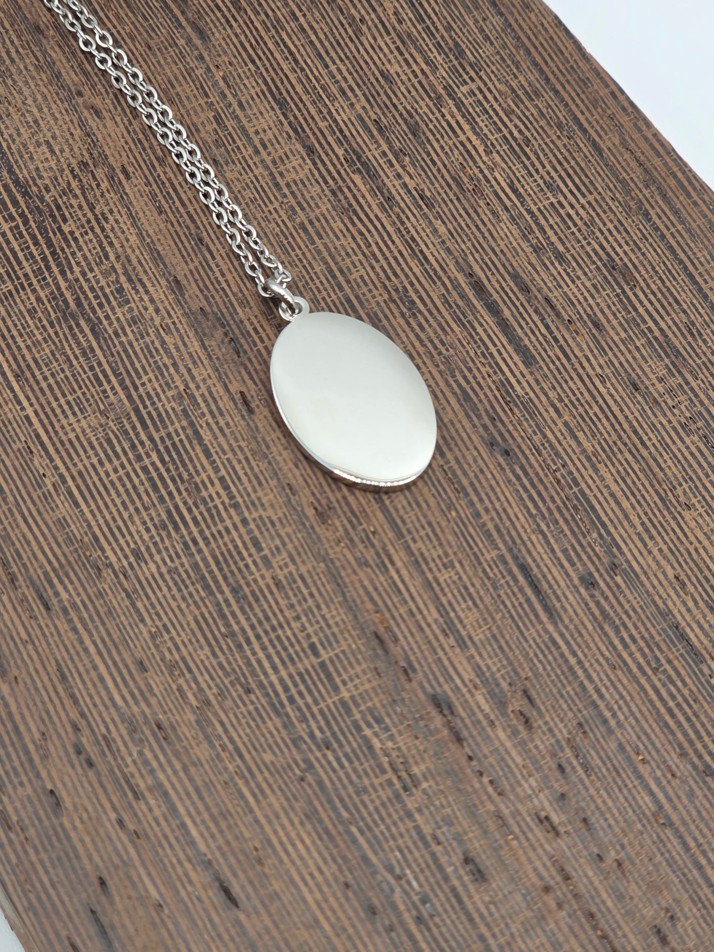 Silver necklace with a round pendant on a wooden surface