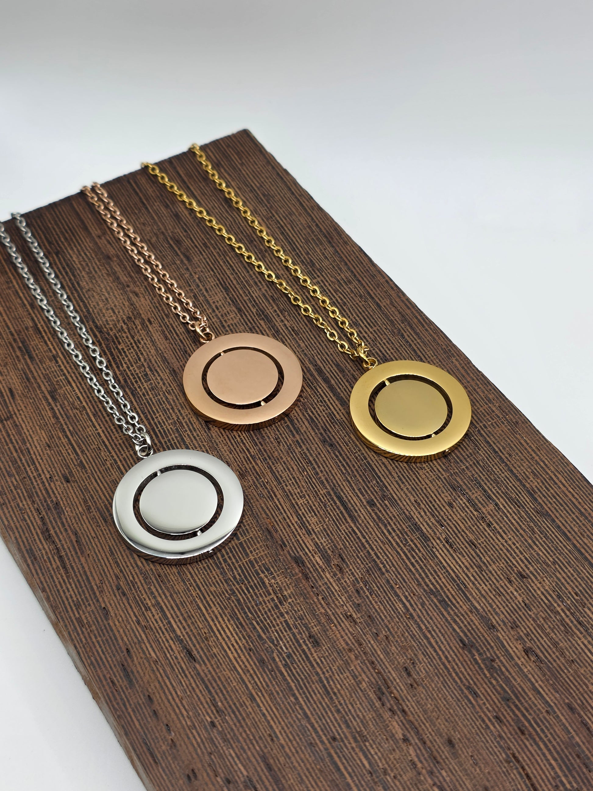 Three necklaces with different pendants on a wooden stand.
