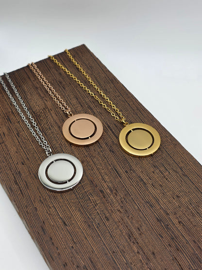 Three necklaces with different pendants on a wooden stand.