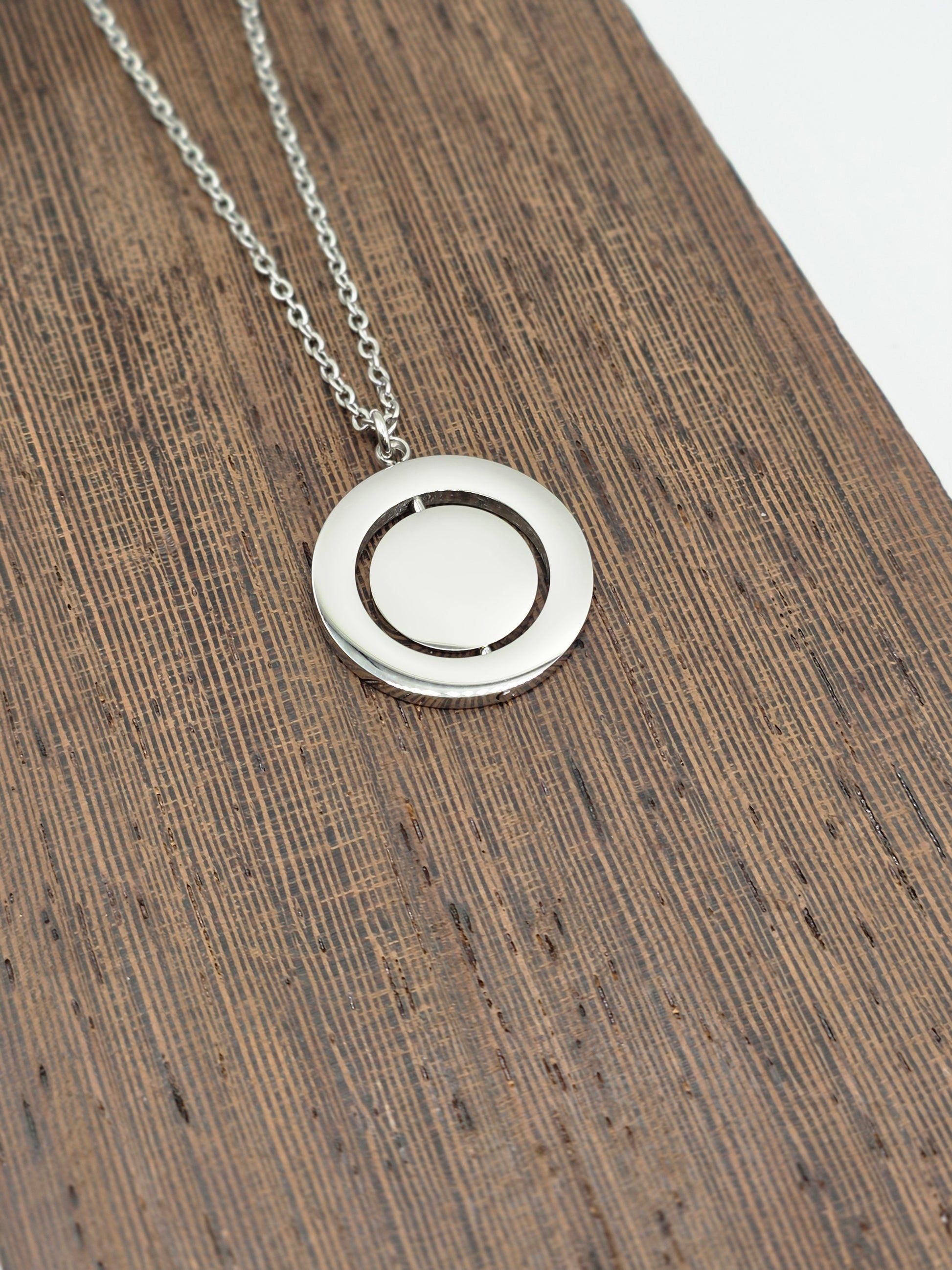 Silver necklace with a round pendant on a wooden surface