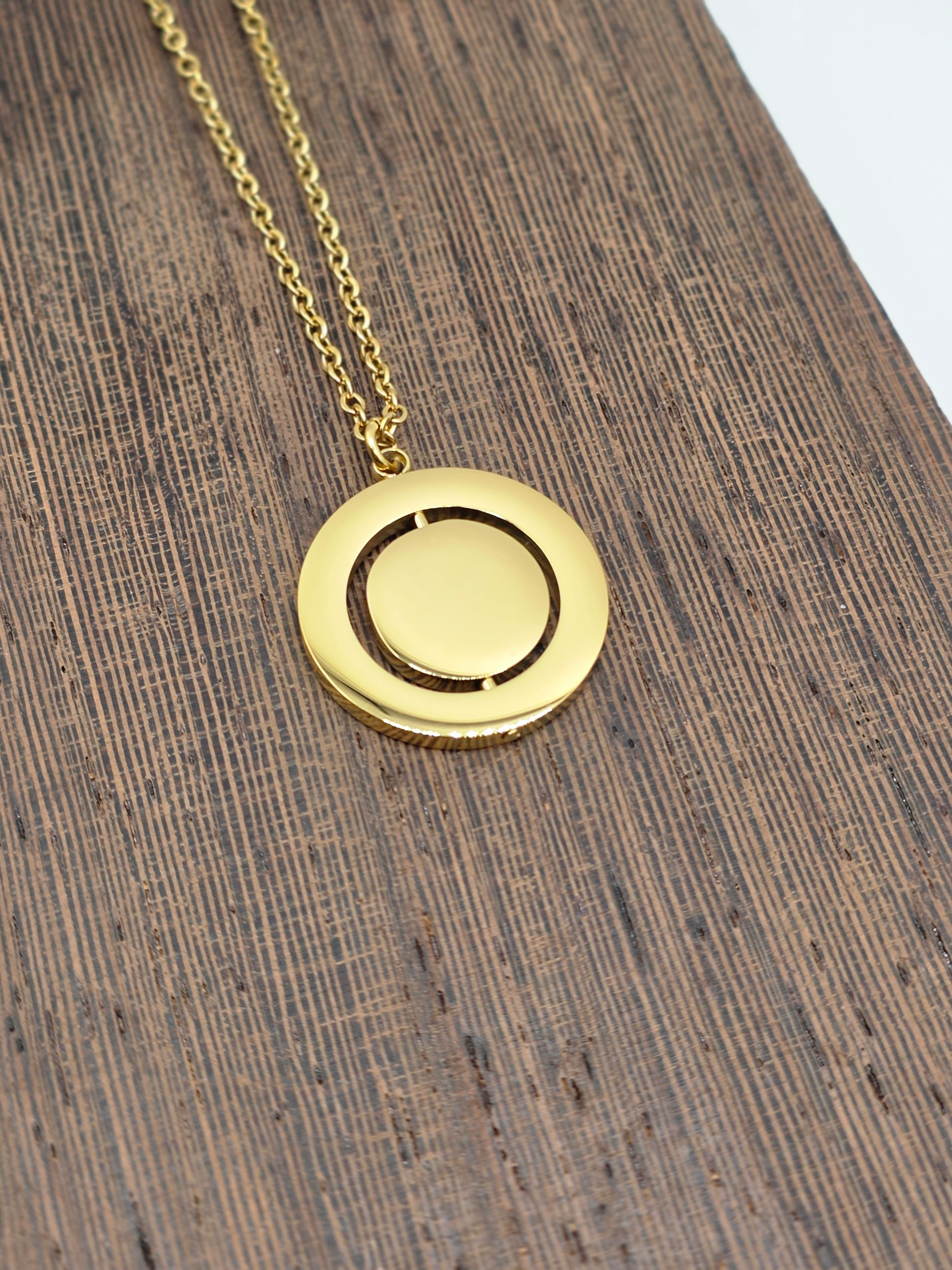 Gold necklace with a round pendant on a wooden surface