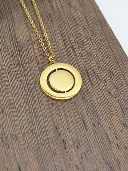 Gold necklace with a round pendant on a wooden surface