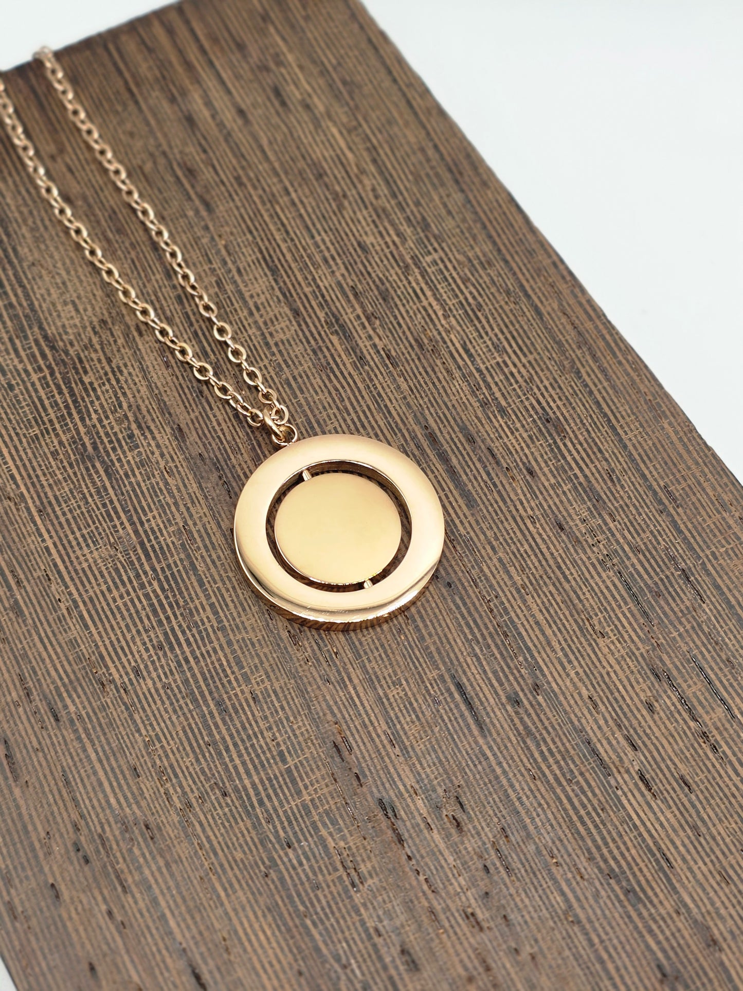 Gold necklace with a round pendant on a wooden surface