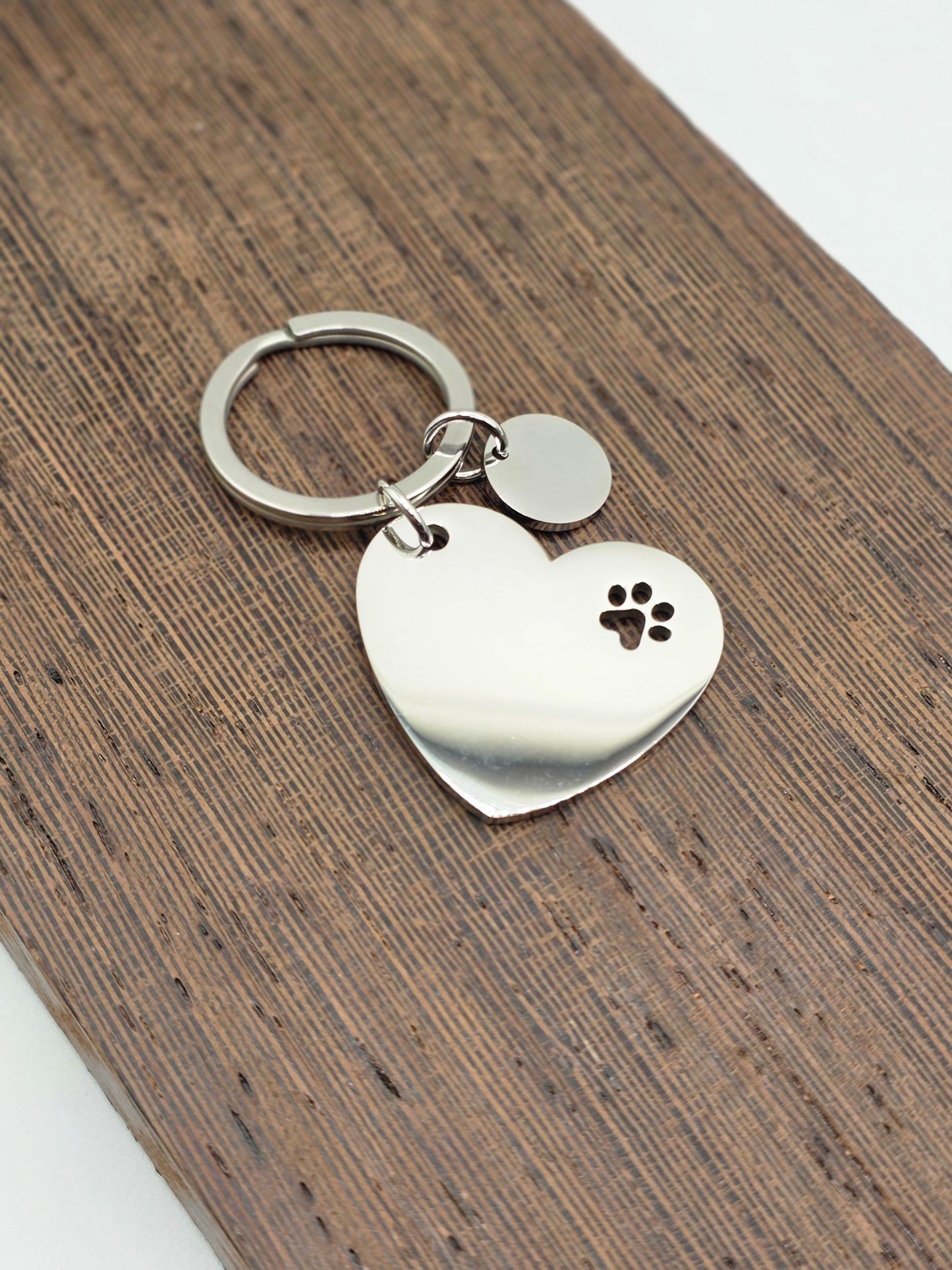 Heart-shaped keychain with paw print design on a wooden surface