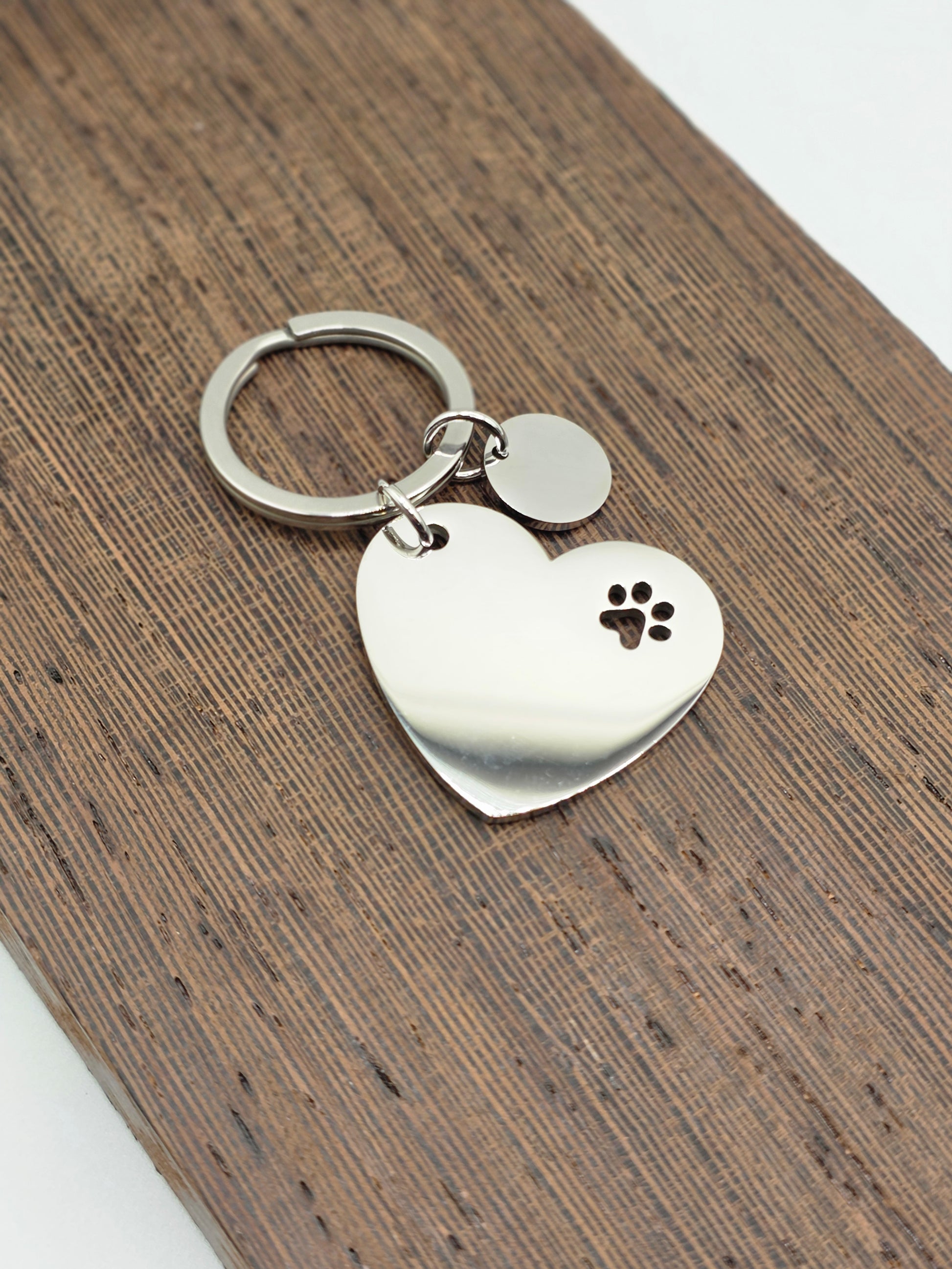 Heart-shaped keychain with paw print design on a wooden surface