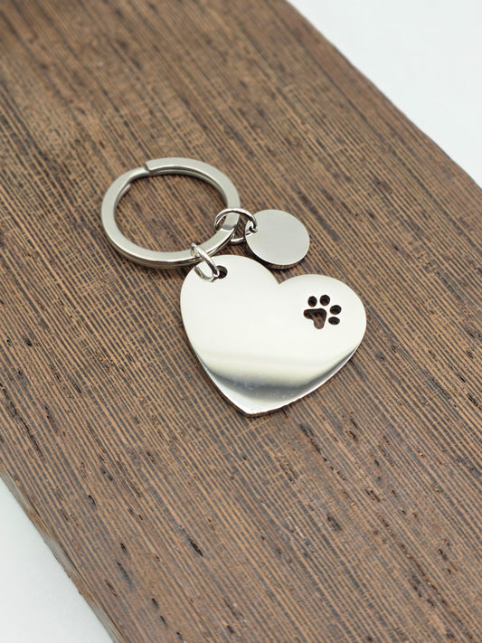 Heart-shaped keychain with paw print design on a wooden surface