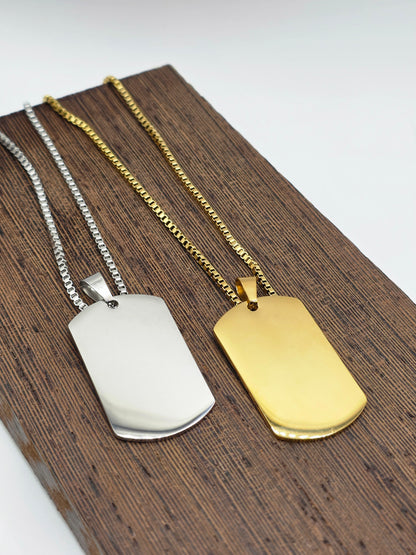 Two dog tags, one gold and one silver, on a wooden surface.