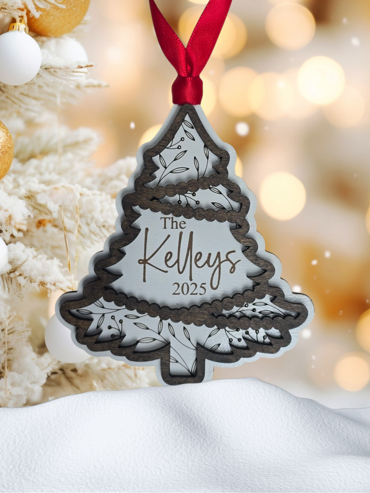 Personalized Christmas tree ornament with 'The Family name 2025' text, red ribbon, and festive background.