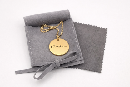 Gold necklace with a pendant on a gray jewelry pouch