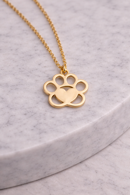 Gold paw print necklace on a gray surface