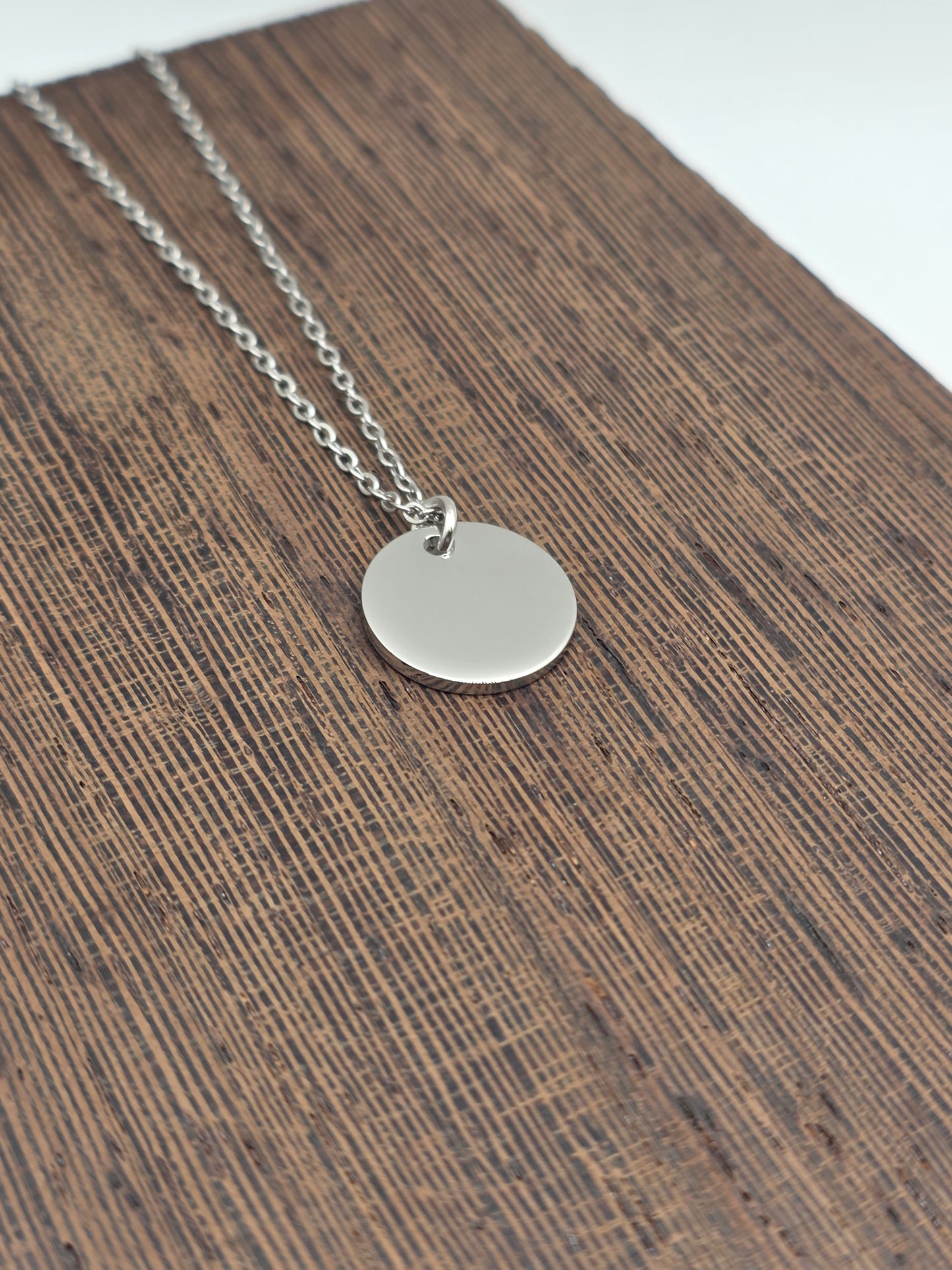 Silver necklace with a round pendant on a wooden surface