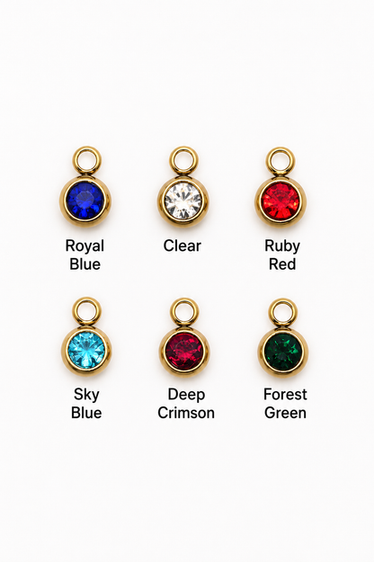 Six gold-tone round bezel charm settings shown on a white background, labeled Royal Blue, Clear, Ruby Red, Sky Blue, Deep Crimson, and Forest Green.
