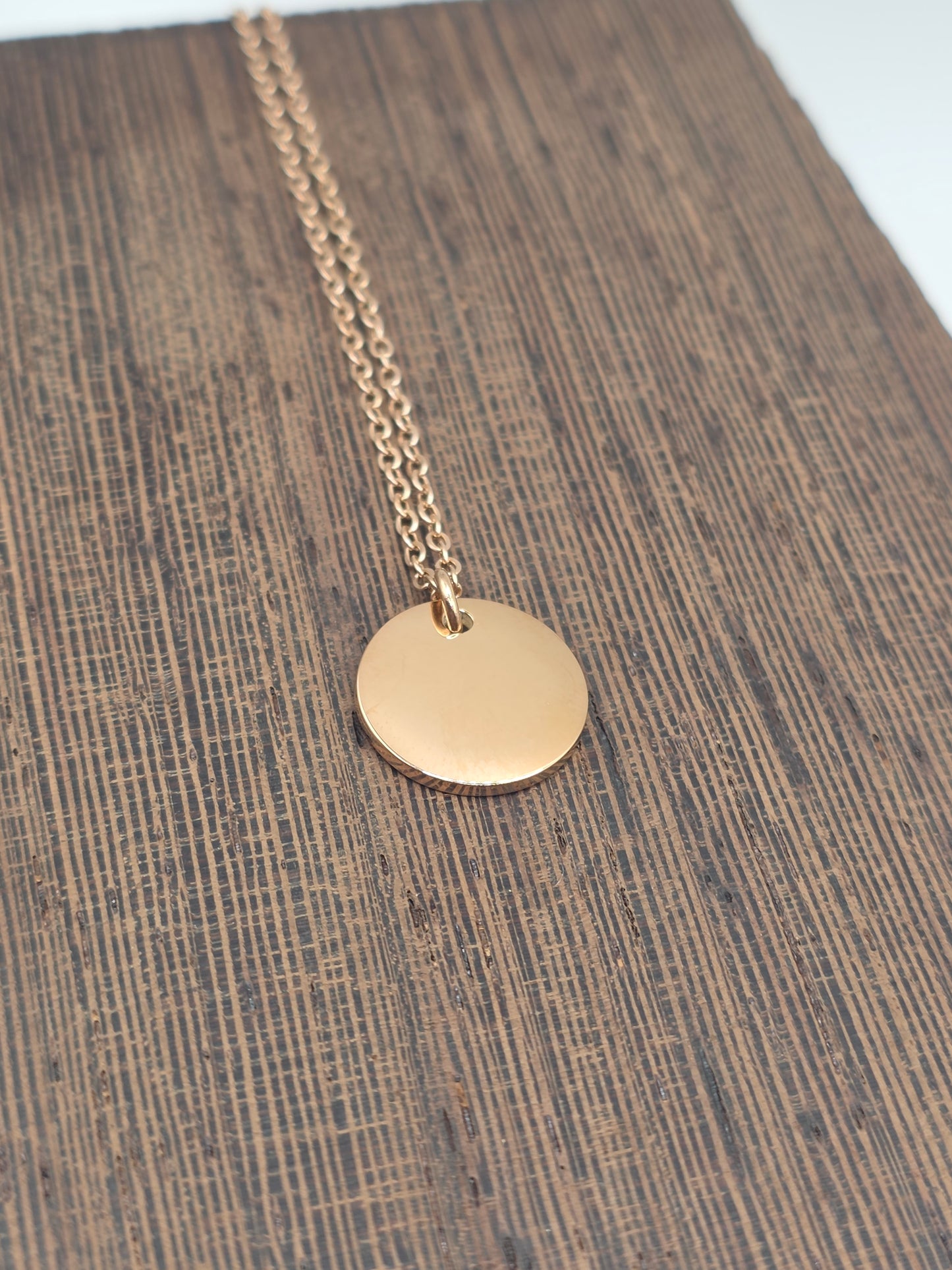 Rose Gold necklace with a round pendant on a wooden surface