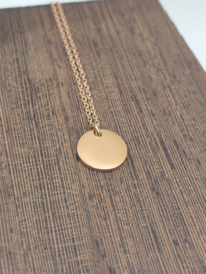 Rose Gold necklace with a round pendant on a wooden surface